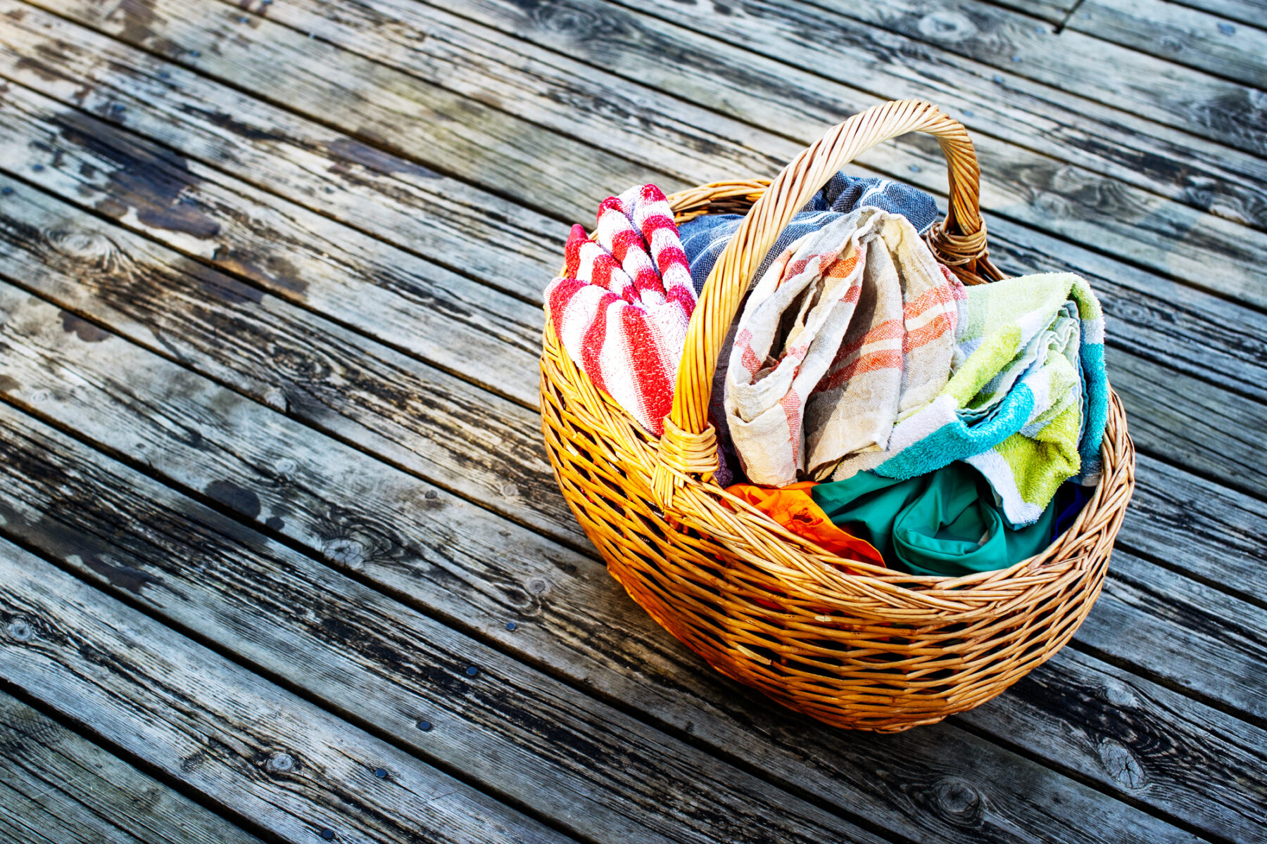 Towels in a basket sit on a weathered wooden dock.