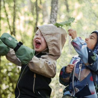 Unos niños que van vestidos con chubasqueros de colores juegan alegremente en el bosque.