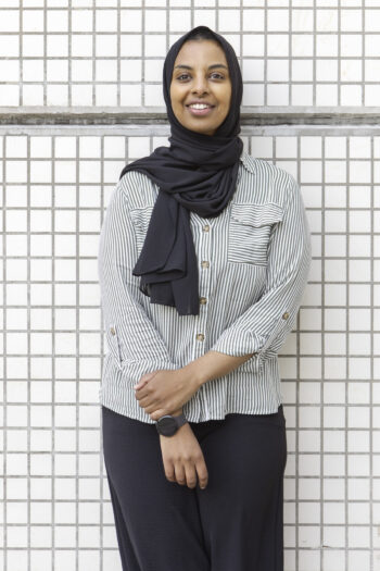 Finnish entrepreneur Fadumo Ali leans against a white tile wall. 