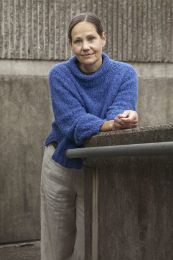 Finnish entrepreneur Ansu Lönnberg leans forward on a concrete wall.