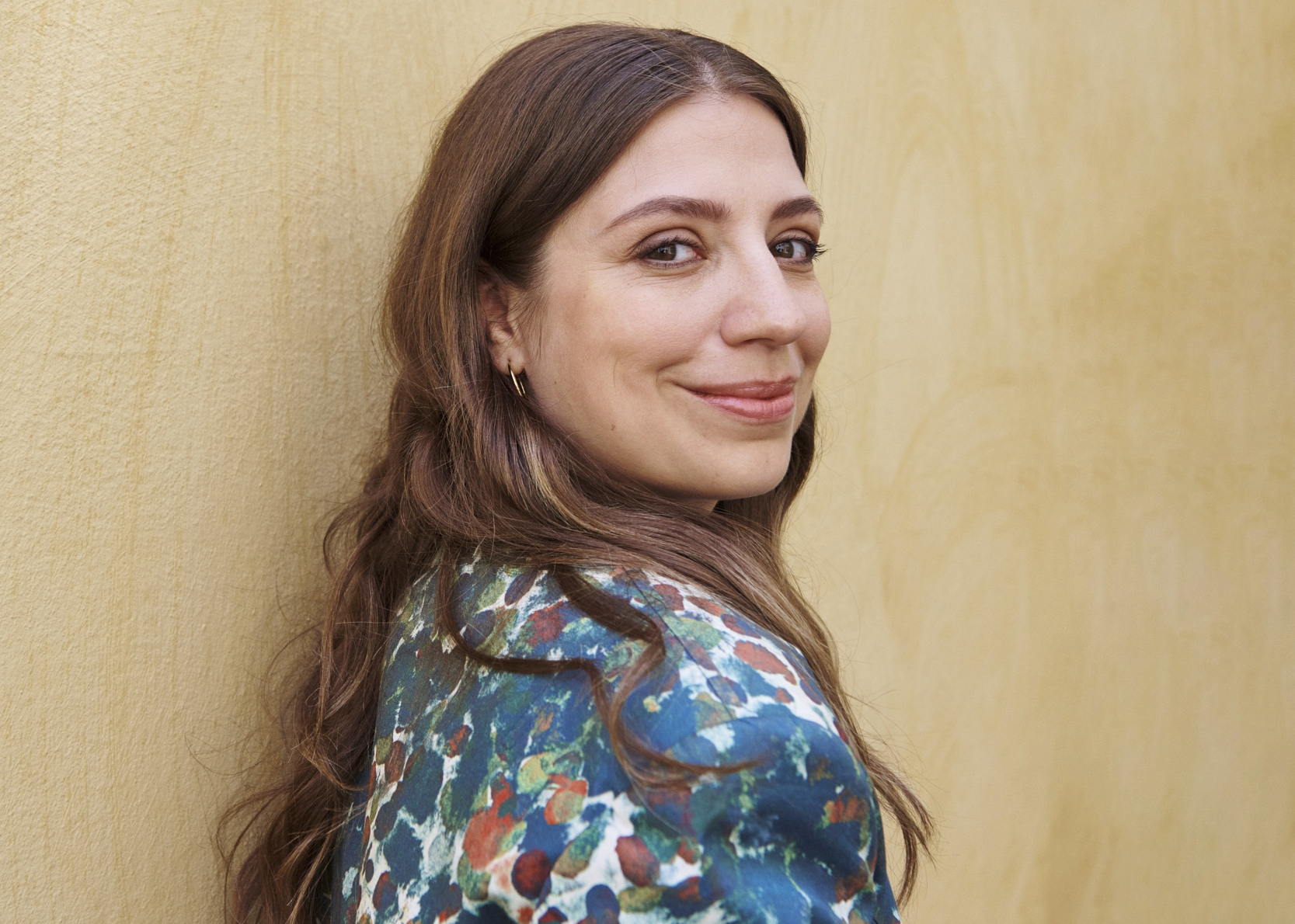 Dalia Stasevska stands in front of a wall, smiling over her shoulder at the camera.
