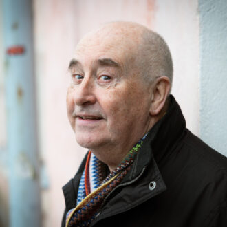 Tim Bird looks towards the camera while standing beside the pink stucco walls of a building on the island fortress of Suomenlinna.