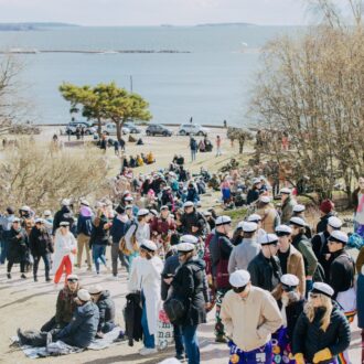 تجتمع حشود في حديقة تقع على سفح تل ساحلي تطل على البحر خلال احتفالات "فابو"، حيث يرتدي الكثيرون قبعات التخرج التقليدية البيضاء الخاصة بالمدارس الثانوية.