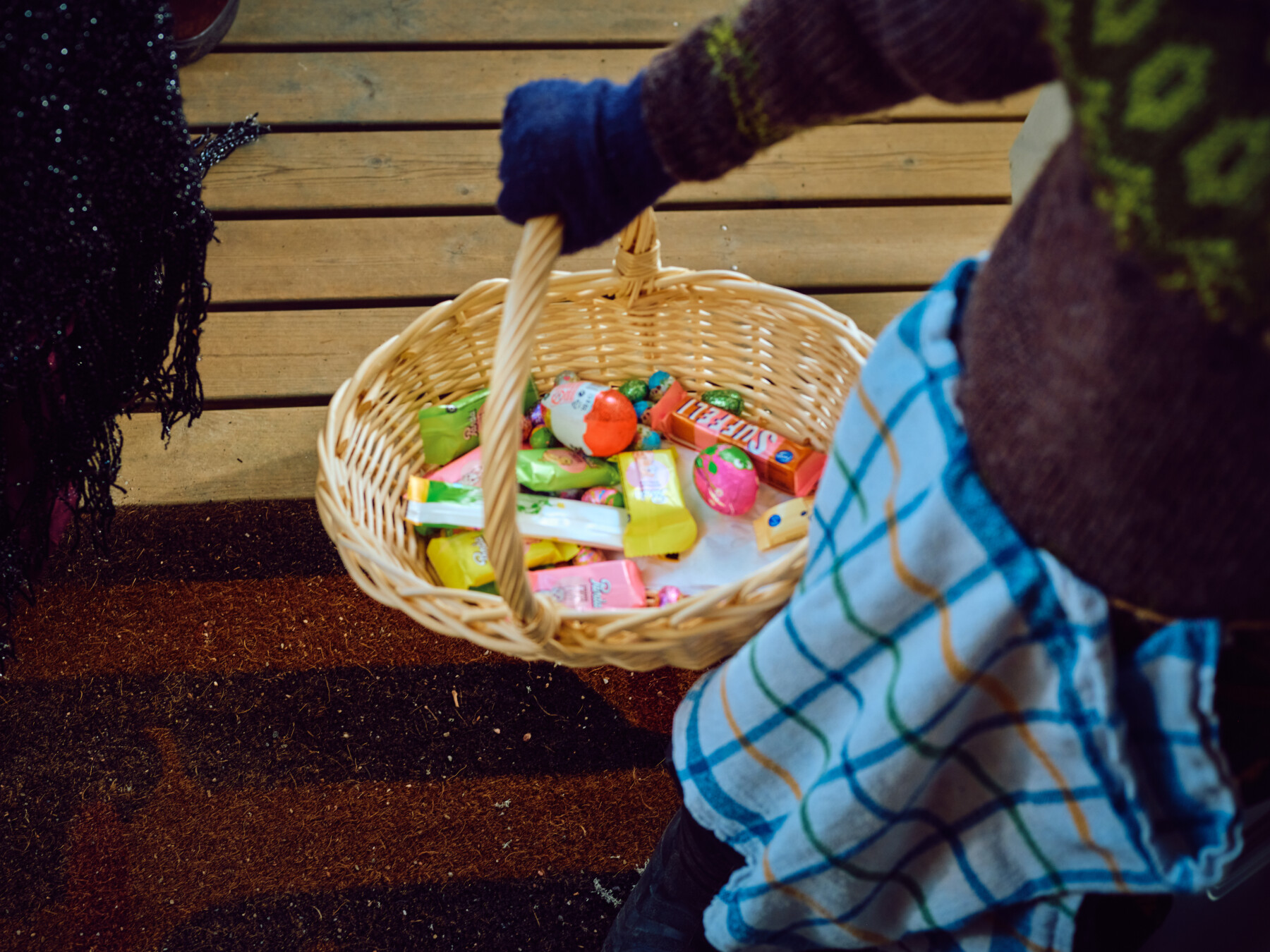 A wicker basket containing assorted sweets is carried by a child taking part in Easter traditions in Finland.