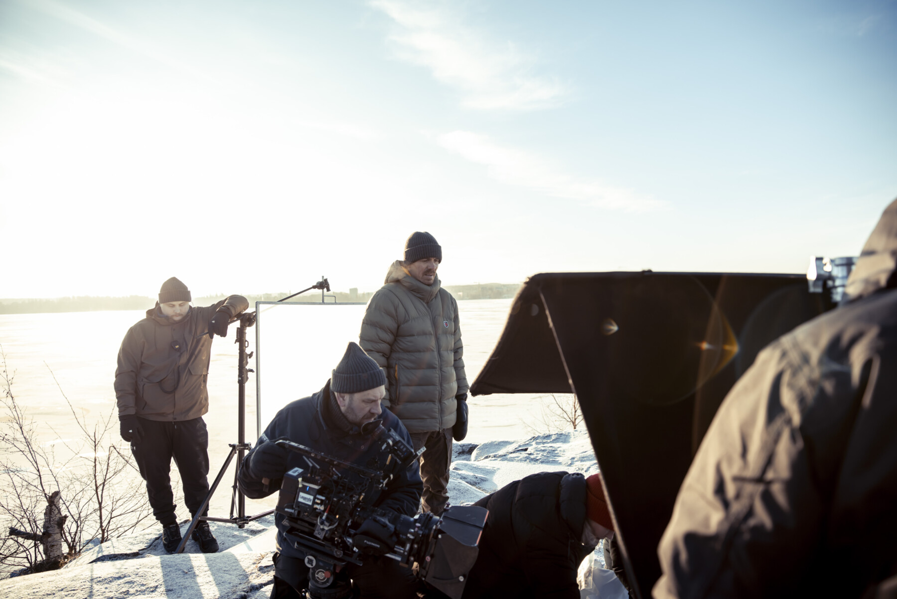 Uma equipe de filmagem para a série Blood and Sweat grava uma cena na paisagem nevada com um lago ao fundo.