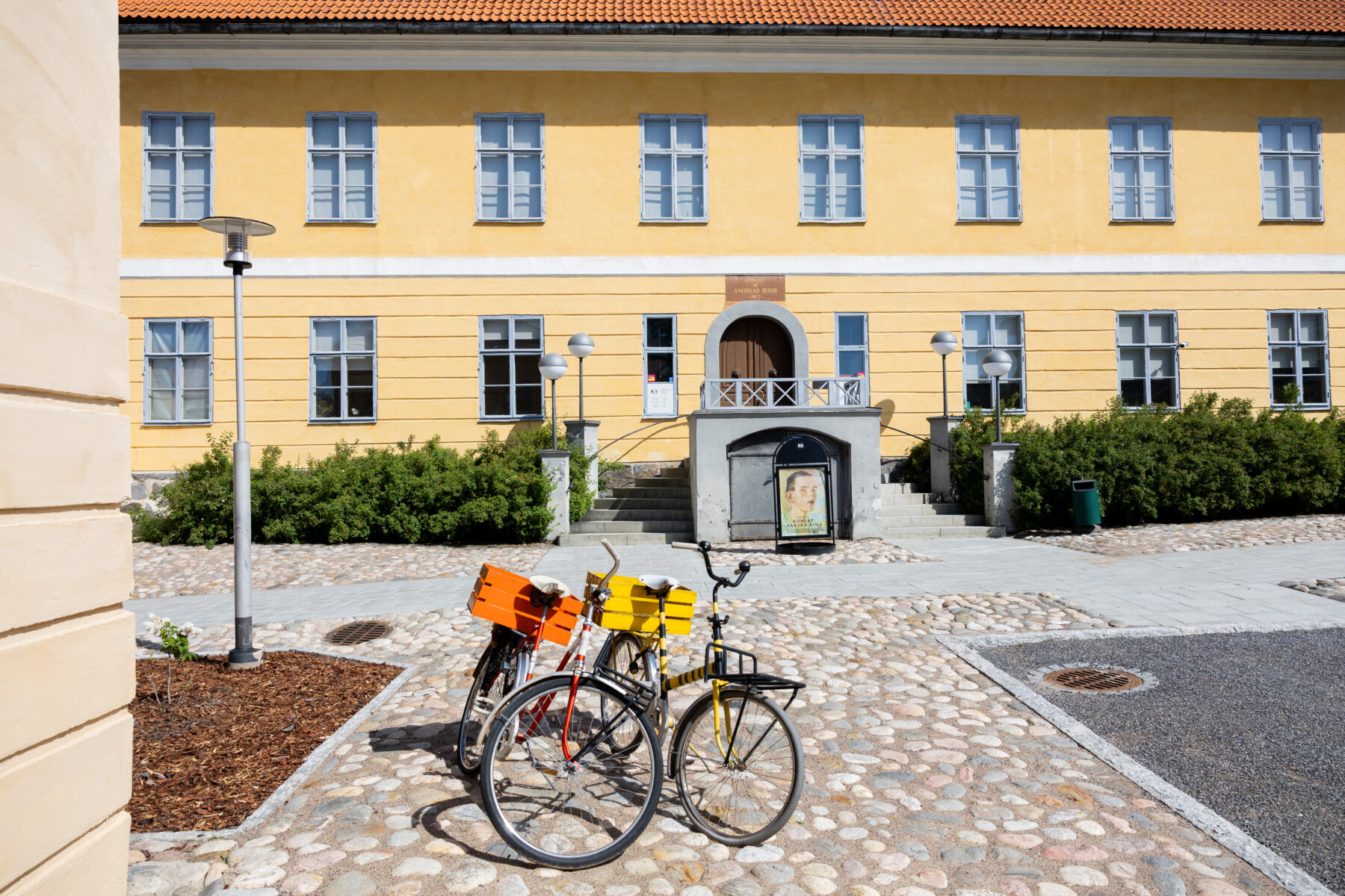 Bicycles stand on a cobbled courtyard in front of the yellow façade of Anders Roos’s historic house in Kokkola’s Oppistan district.