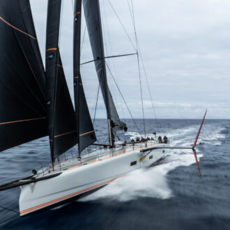 Eine leistungsstarke Luxusyacht von Baltic Yachts rast an einem bewölkten Tag unter dunklen Segeln über das Meer.