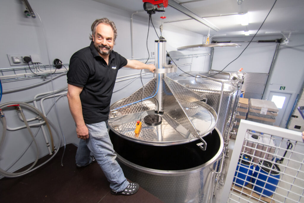 David Cohen stands beside a large stainless steel fermentation tank inside Ainoa Winery’s production facility in Hollola, Finland.