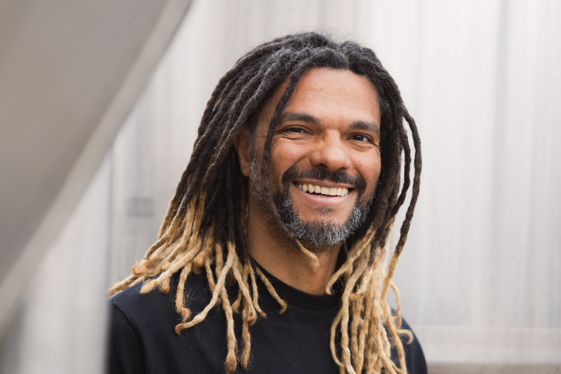 CoolHead’s Cleber Gonçalves smiles towards the camera, his long dreadlocks framing his face against a softly lit background.