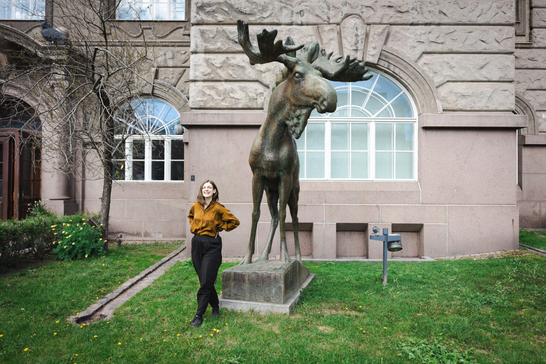 Standing next to Jussi Mäntynen’s bronze moose statue, author Iida Turpeinen poses outside the Finnish Museum of Natural History.