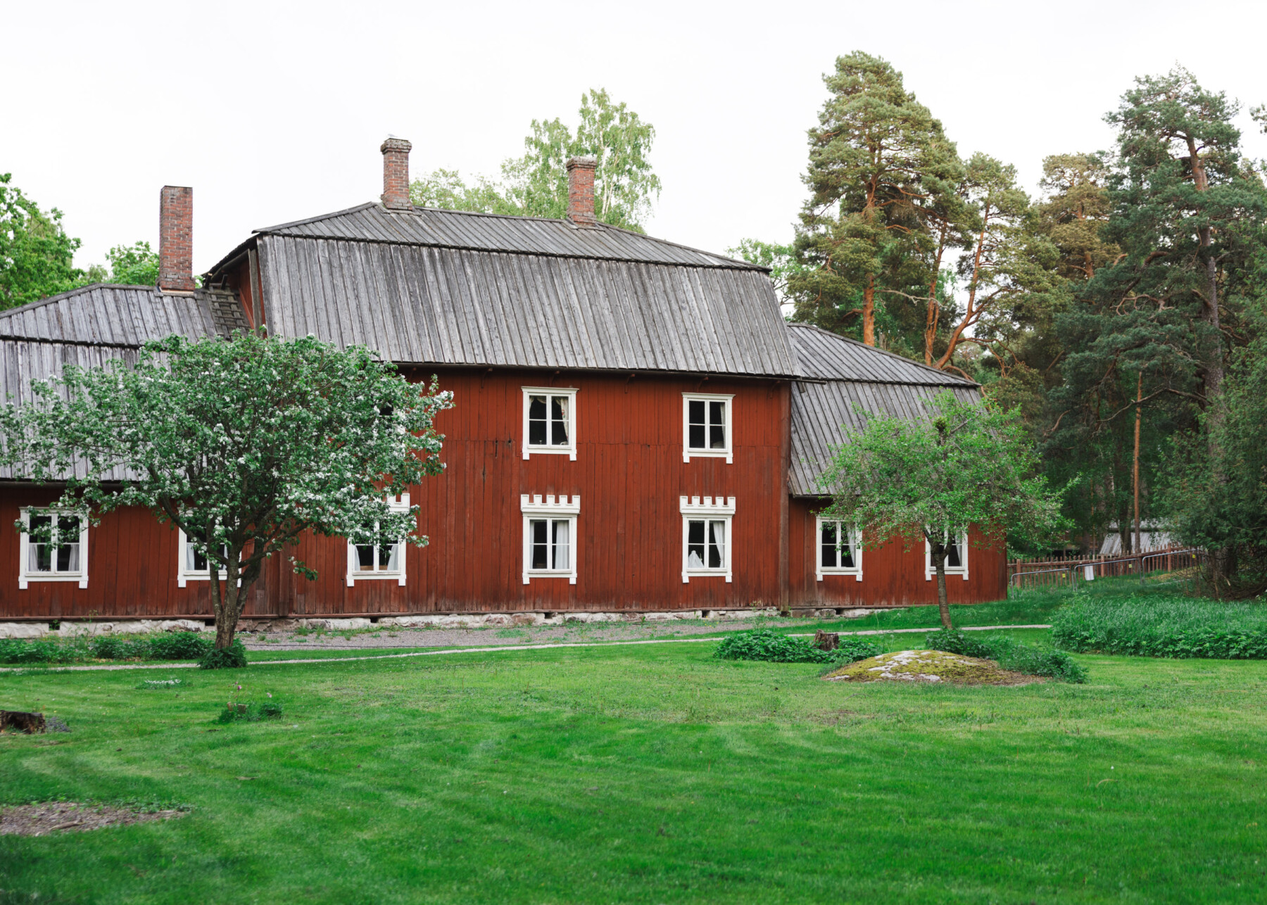 Kahiluoto Manor House, a traditional red wooden manor building with white-framed windows, stands amid lawns and trees at the Seurasaari Open-Air Museum.