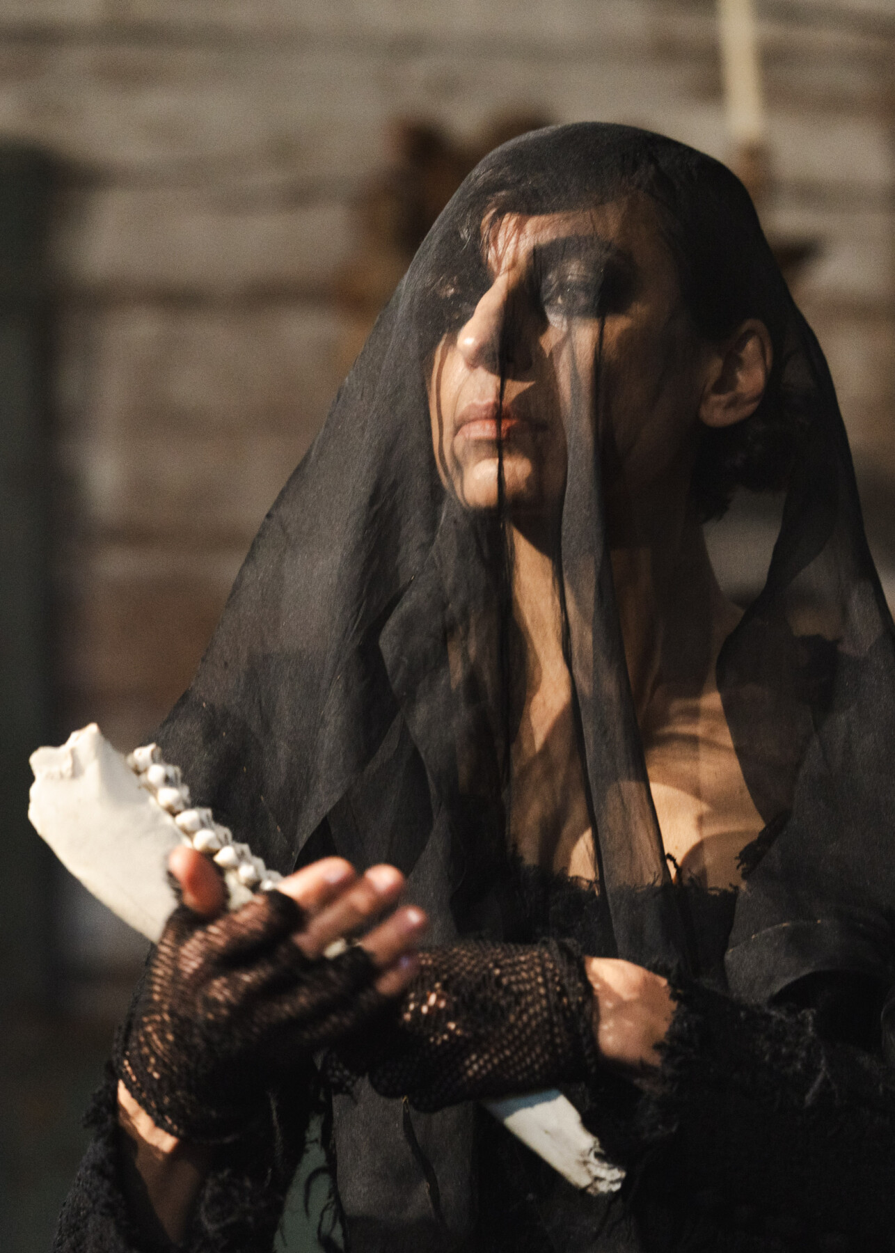 A model wearing a black veil and mesh gloves holds an animal jawbone during Linda Kokkonen’s runway show inside Karuna Church.