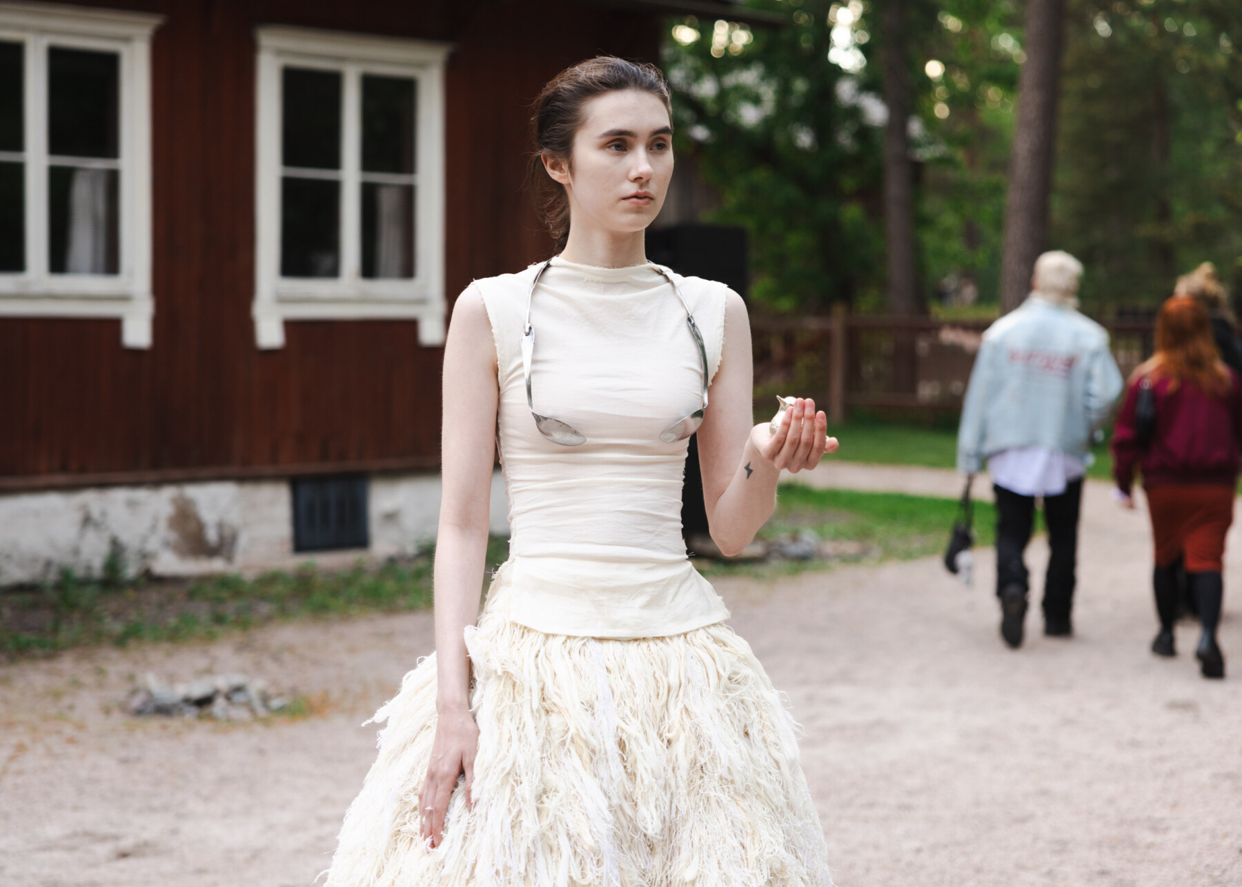 A model stands outdoors at the Seurasaari Open-Air Museum in Helsinki, wearing a cream-coloured dress designed by Enni Lähderinne.