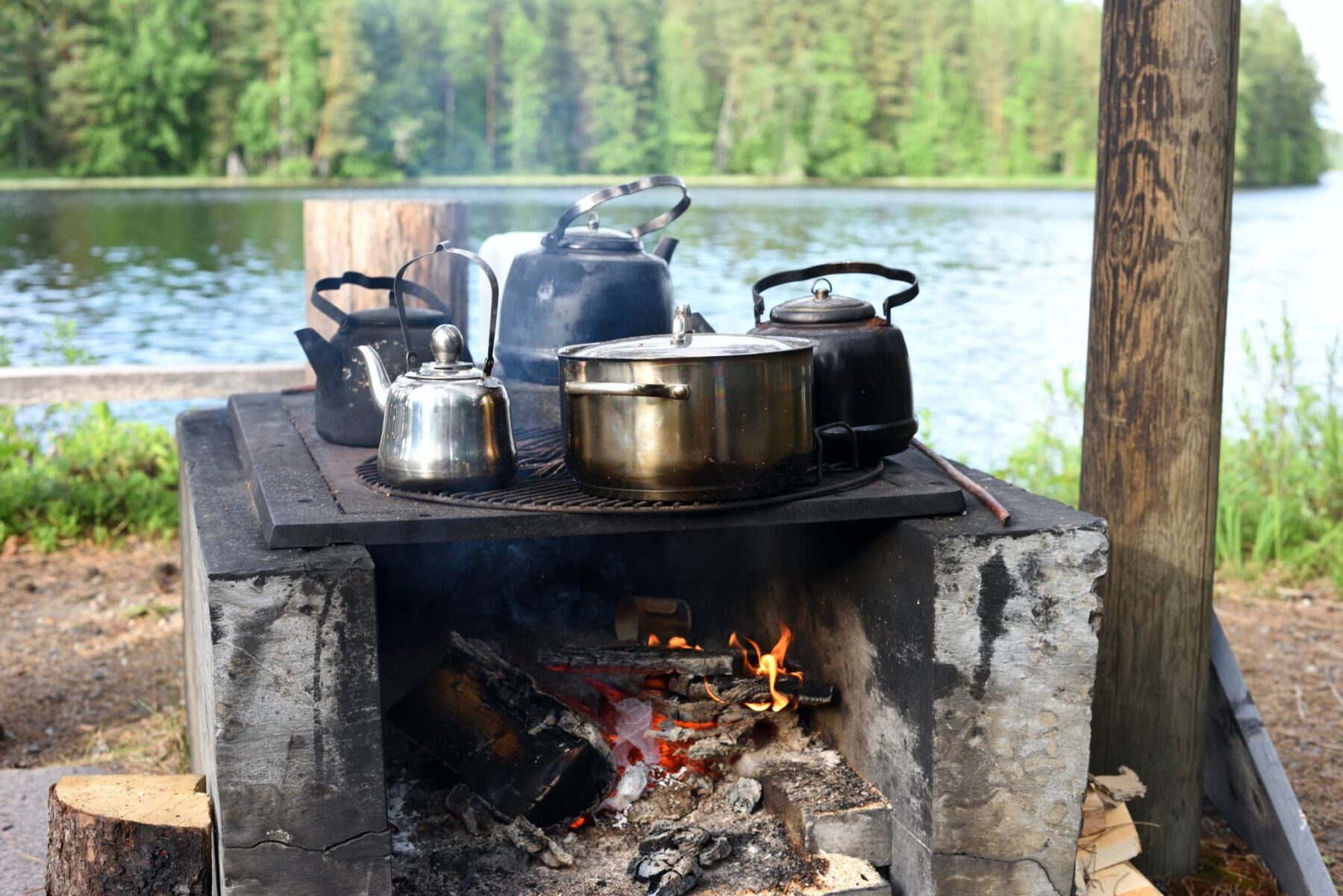 Several pots sit on a grill over an open fire.