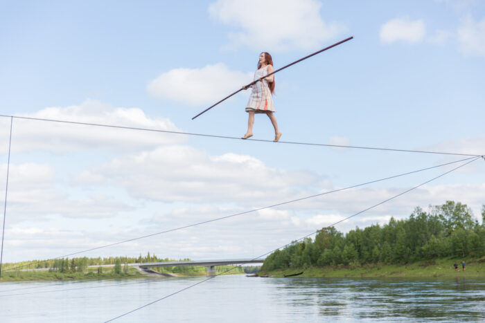A tightrope walker carries a long balancing pole while crossing above the Ounas River during a circus performance at the Silence Festival in northern Finland.