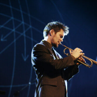 A man plays a trumpet on a stage.