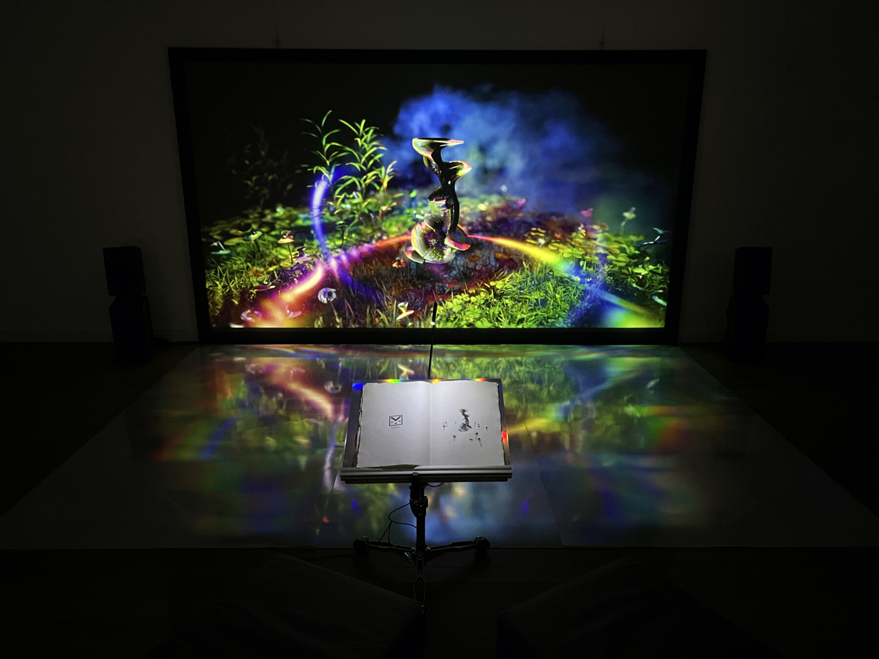 A colourful artwork on a screen, surrounded by darkness.