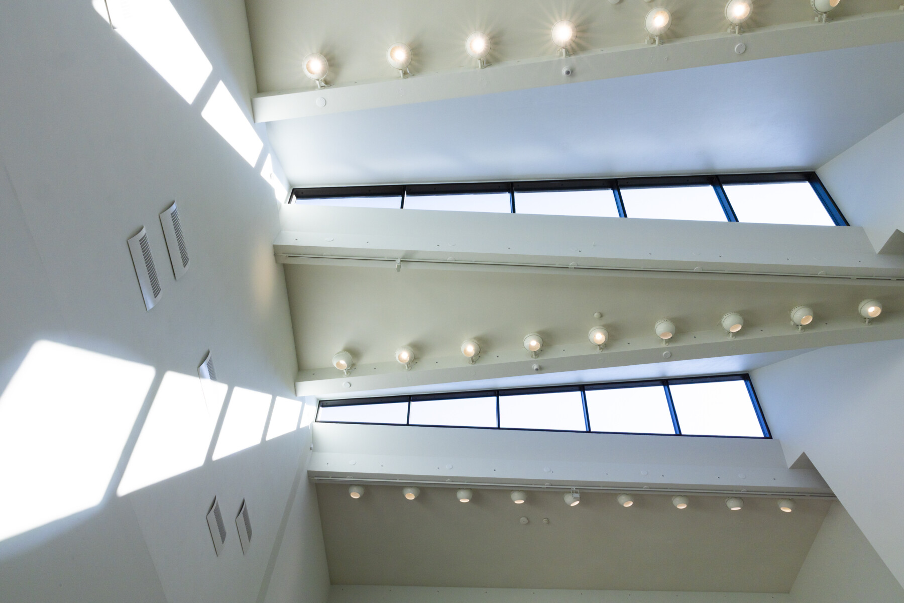 An interior view of a building with white walls and distinctive rows of windows.